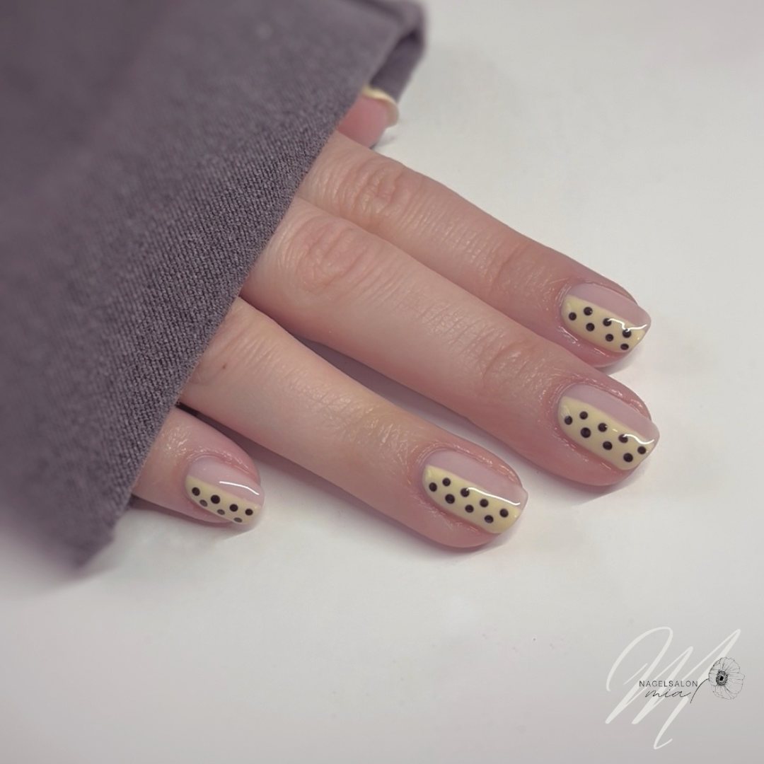 Crèmekleurige nagels met zwarte stippen als nail art