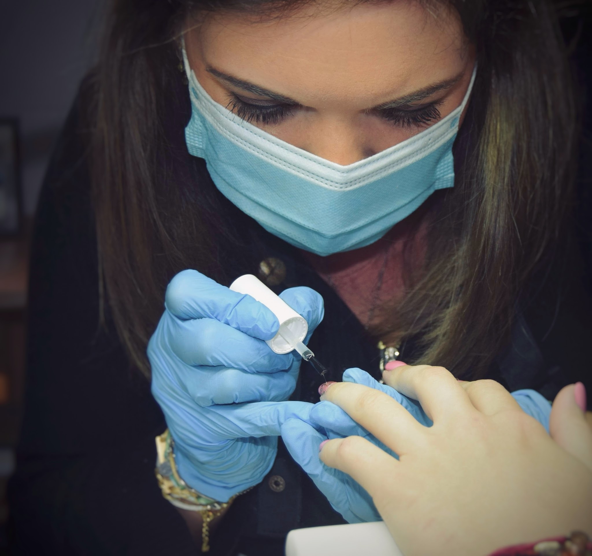 Femke met mondkapje en handschoenen aan het werk aan de nagels van een klant