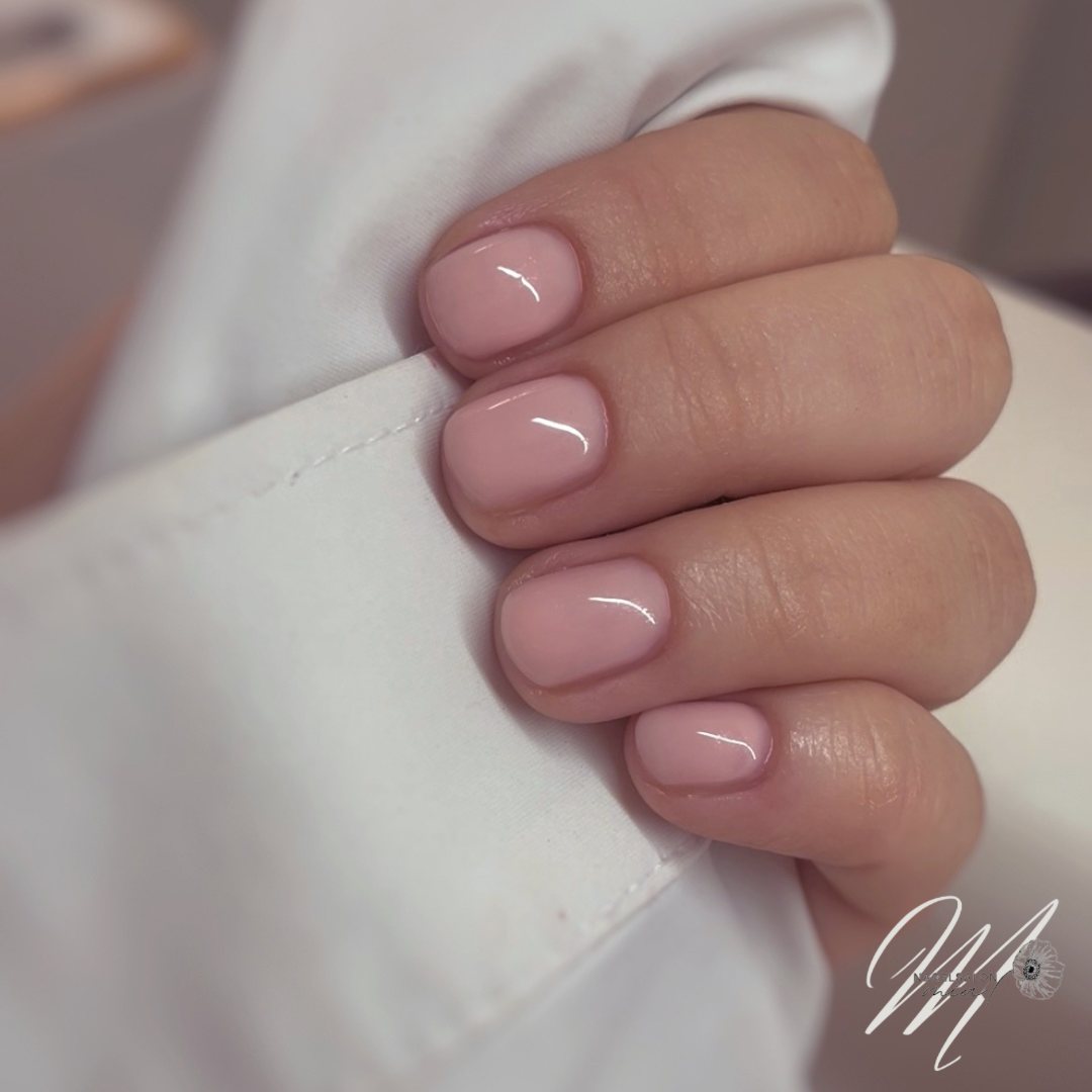 Naturel roze BIAB op eigen nagels, de hand rust op een witte manchet